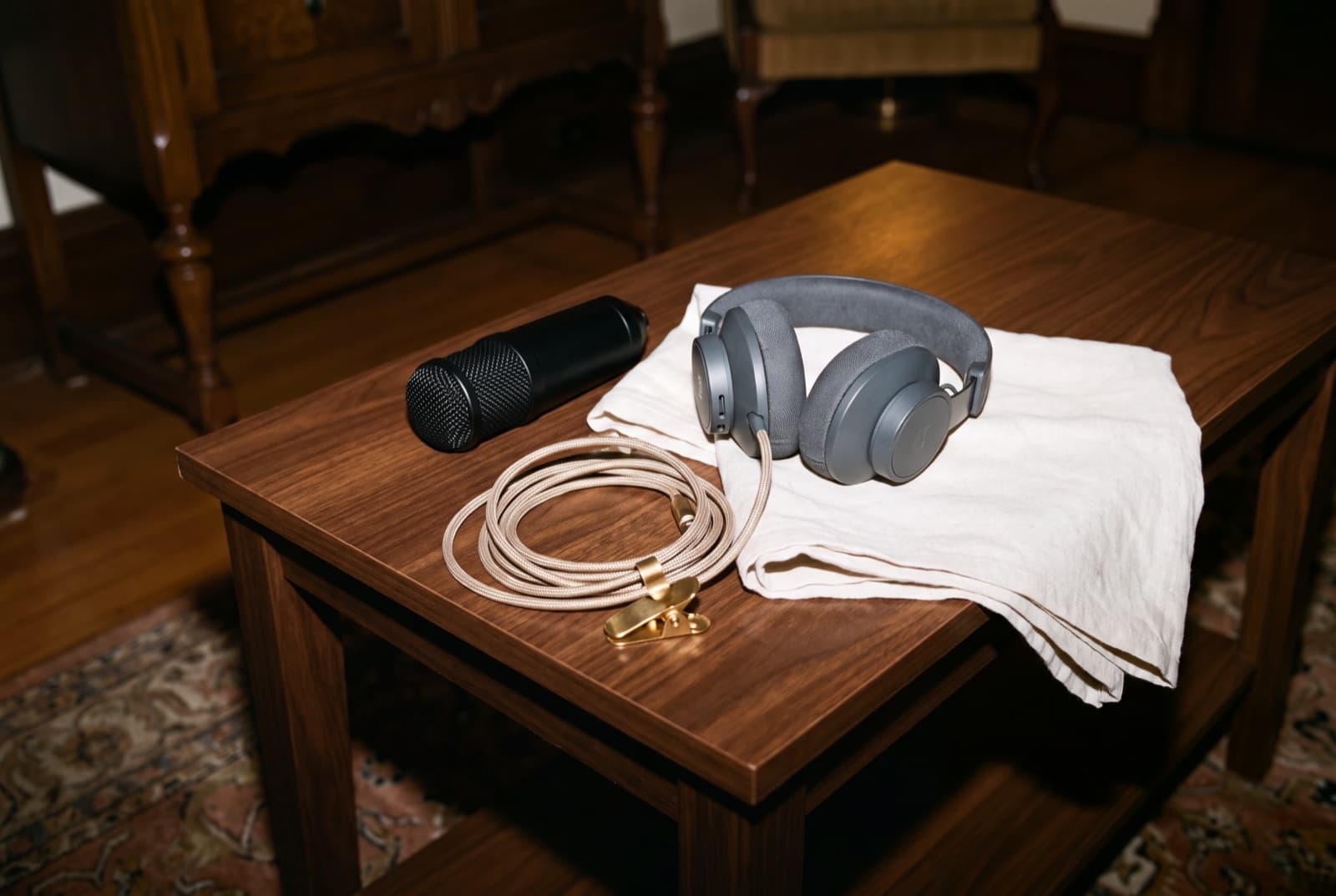 Clean headphones, a microphone, and a braided cable photographed with direct flash on a dark wood table
