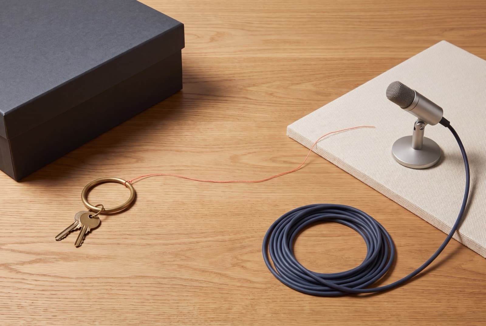 Two separate podcast work zones connected by a cable, with a microphone and an unmarked keyring